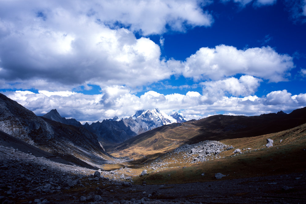 Le deuxième jour est consacré au transfert depuis Huaraz qui est le point de rendez-vous pour toutes les randonnées, treks, ... qui se font dans cette partie de la Cordillère. Notre route nous conduit sur cette piste de montagne passant par le col Cuncush à 4750 mètres qui nous montre la vallée où se trouve déjà notre premier campement, au fond, caché derrière le versant droit.<br />Prise de vue : 14/07/08, 14h10