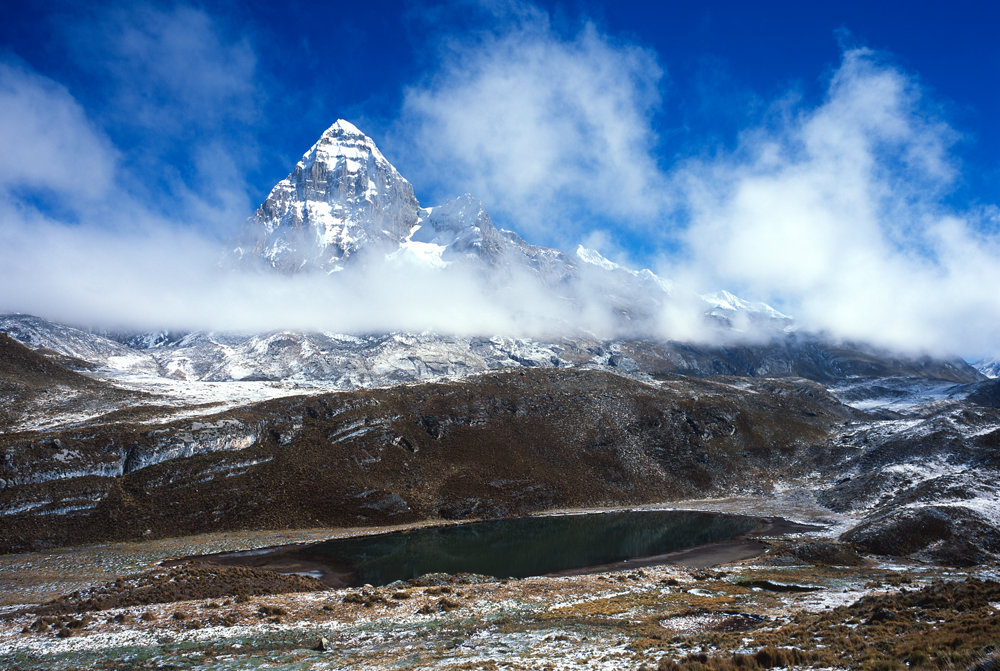 En quittant ce matin-là Huayhuash, les nuages nous accompagnent et nous laissent que le sol gelé comme point de vue. Au travers, cependant, nous devinons une montagne, qui se découvre finalement, le Trapecio (5653 m). À ses pieds, se trouvent de petits lacs dont la Laguna Mitococha (4485 m).<br />Prise de vue : 19/07/08, 09h20